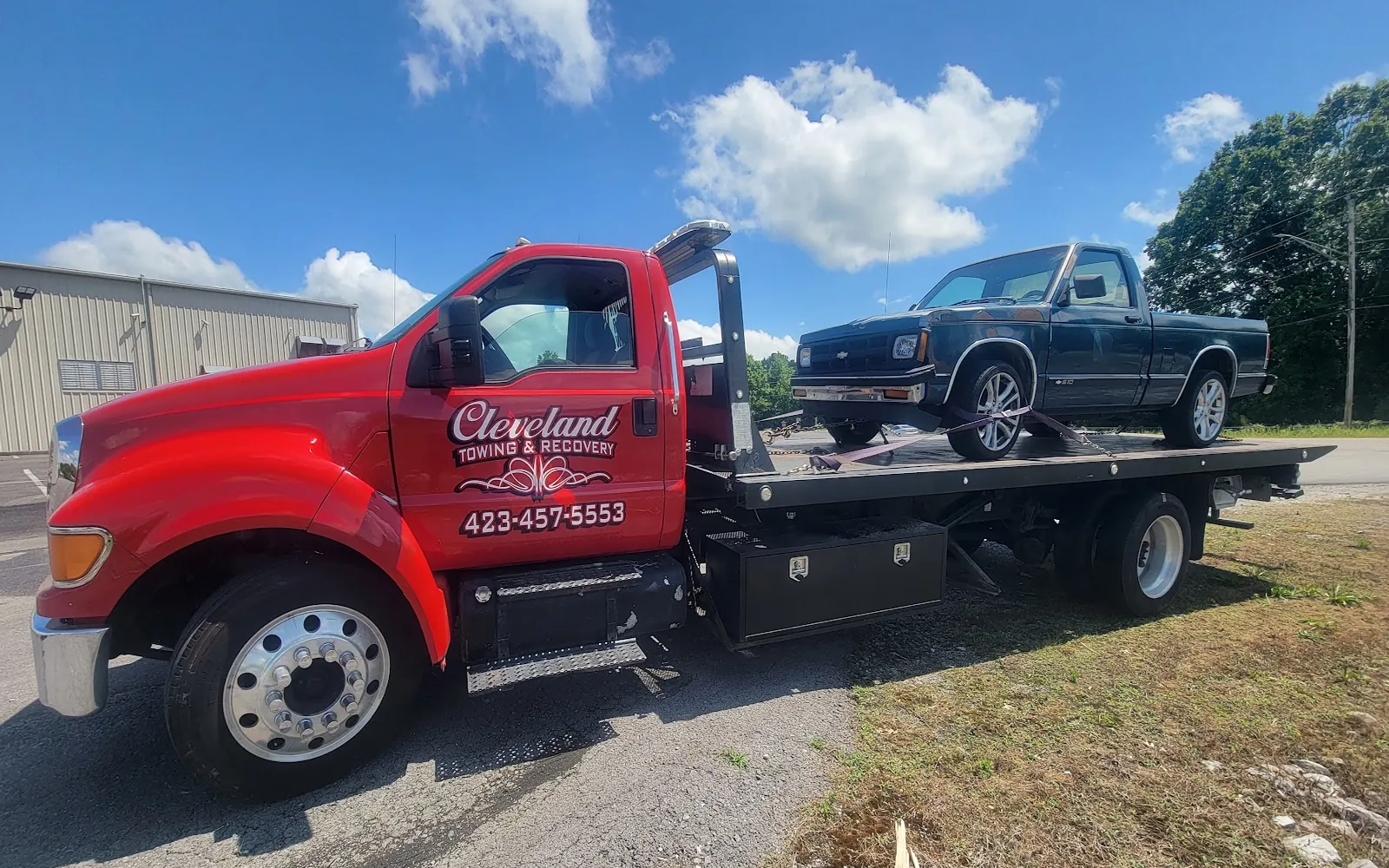 Cleveland Towing & Recovery’s red flatbed rollback with a pickup truck loaded and strapped down on the deck