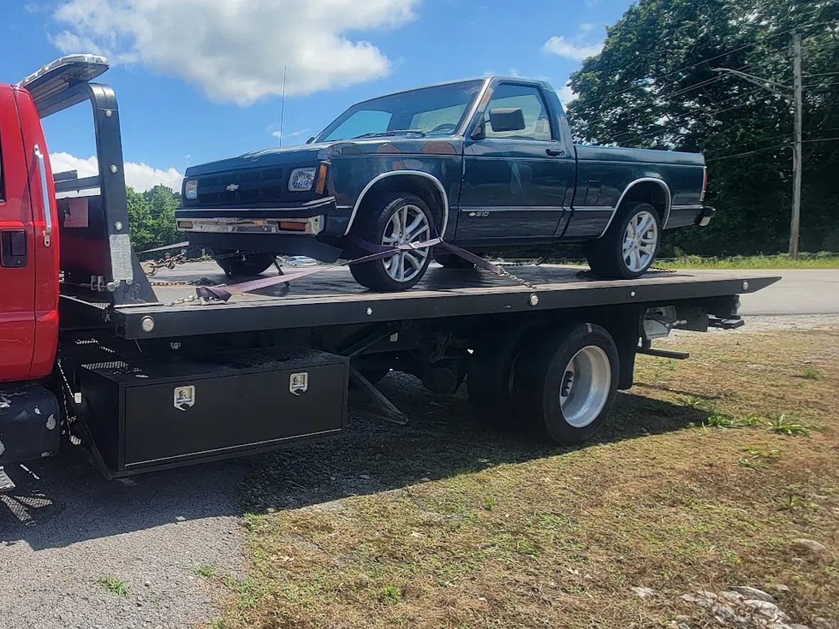 A pickup truck loaded and strapped down on the flatbed deck of the rollback